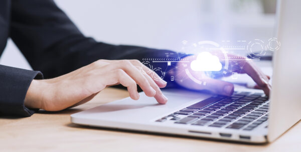 Close-up of hands typing on a laptop with a digital cloud computing interface, representing cloud data access, Citrix DaaS training, and modern digital transformation trends in 2025.