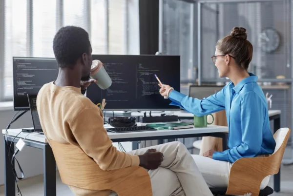 Two IT professionals reviewing code on a monitor during an instructor-led technical training session, Benefits of Nutanix certification.